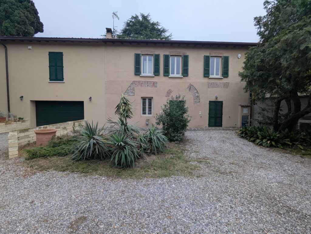 Corte d’ingresso prima dell’intervento: aiuola spoglia, prato ingiallito, ghiaia disordinata